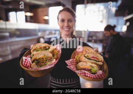 Ritratto di una giovane cameriera sorridente che serve hamburger freschi presso la caffetteria Foto Stock