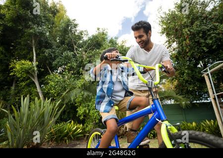 Felice padre che assiste il figlio per andare in bicicletta Foto Stock