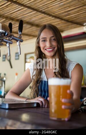 Ritratto di un bramaid sorridente che tiene un bicchiere di birra Foto Stock