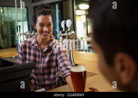 Sorridente barmaid che serve drink all'uomo Foto Stock