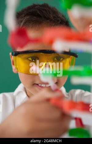 Studente sorridente che sperimenta il modello delle molecole in laboratorio Foto Stock