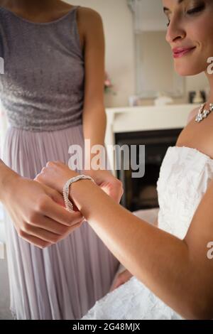 La sezione centrale della bridesmaid che assiste la sposa nell'ottenere vestita Foto Stock