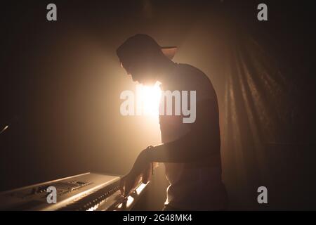 Musicista maschio suonare il pianoforte in discoteca illuminata Foto Stock