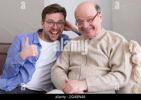 Ritratto closeup, famiglia, giovane uomo che tiene il pollice più vecchio manshowing in su Foto Stock