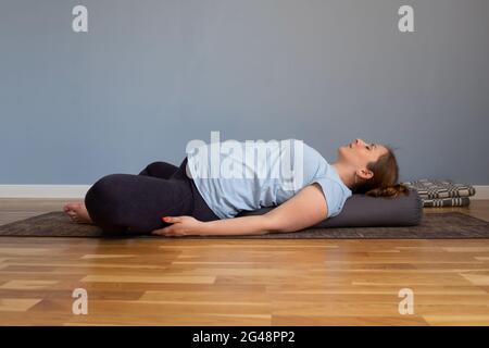 Donna incinta che pratica yoga nell'esercizio delle farfalle reclinate Foto Stock