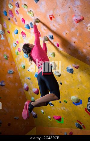 Donna determinata che pratica l'arrampicata su roccia Foto Stock