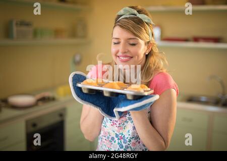 Donna che tiene un vassoio di muffin al ristorante Foto Stock