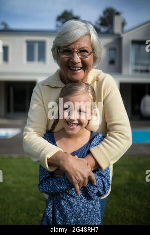 Nonna e nipote sorridenti che si abbracciano in giardino Foto Stock