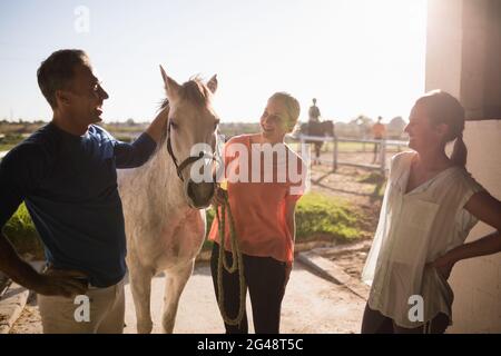 Allenatore che parla con le donne mentre si è in piedi a cavallo Foto Stock