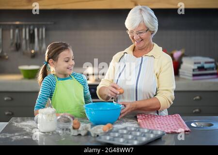 Nonna sorridente che mostra alla nipote di rompere le uova Foto Stock