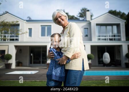 Nonna e nipote sorridenti che si abbracciano in giardino Foto Stock