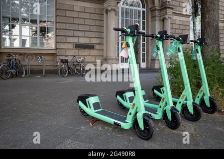 Fila di e-scooters da BOLT Company, con il concetto di mobilità ecologica di condivisione scooter elettrico, parco sul marciapiede di fronte all'edificio. Foto Stock