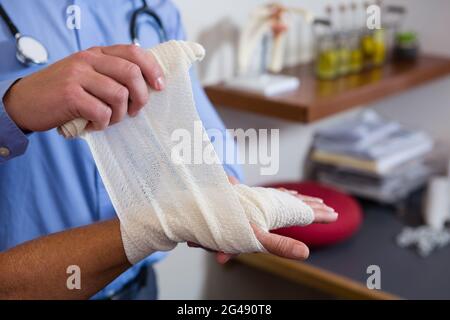 Fisioterapista mettendo fasciatura al ferito alla mano del paziente Foto Stock