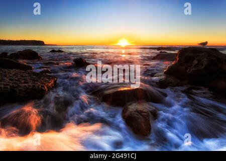 L'alba panoramica del sole che sorge sull'orizzonte dell'oceano Pacifico al largo della spiaggia di Newport a Sydney. Foto Stock