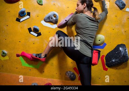 Donna determinata che pratica l'arrampicata su roccia Foto Stock