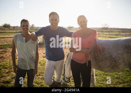 Ritratto di allenatore maschile con giovani donne in piedi a cavallo Foto Stock