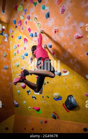 Donna determinata che pratica l'arrampicata su roccia Foto Stock