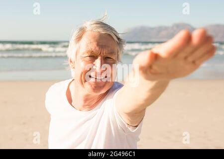 Felice l'uomo senior a praticare yoga in spiaggia Foto Stock