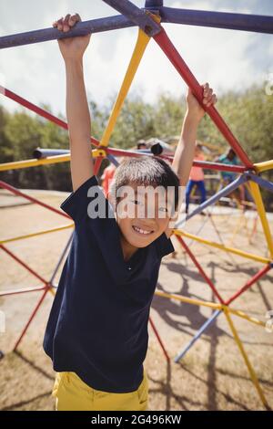 Ritratto di felice scolaro che gioca su dome climber Foto Stock