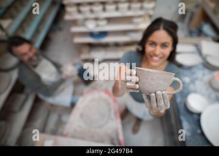 Vasaio femmina che tiene la tazza di creta Foto Stock