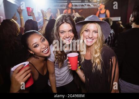 Ritratto di amici femminili con tazze usa e getta in club Foto Stock