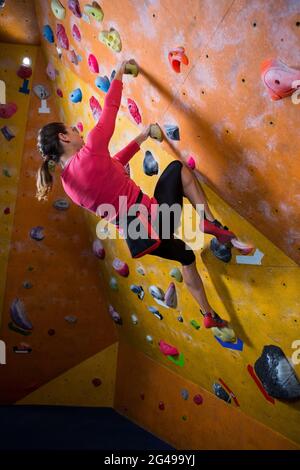 Donna determinata che pratica l'arrampicata su roccia Foto Stock