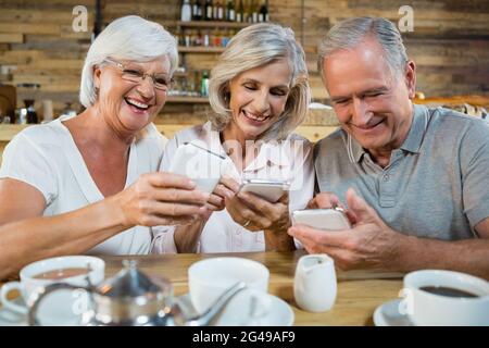 Gruppo di amici senior che utilizzano telefoni cellulari Foto Stock