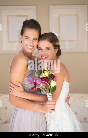 Ritratto di sposa felice e sposa con bouquet in piedi in camera da letto Foto Stock