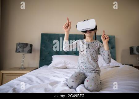 Ragazza che usa la cuffia per la realtà virtuale a letto Foto Stock