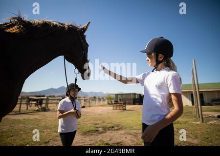 Due ragazze in piedi con un cavallo nel ranch Foto Stock