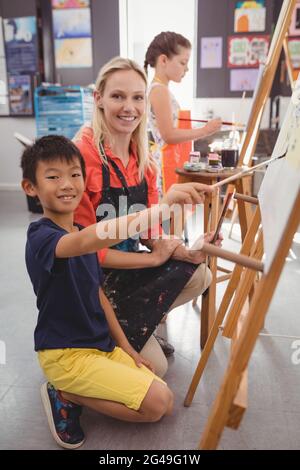 Insegnante assistere schoolboy nella classe di disegno Foto Stock