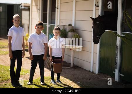 I bambini in piedi con un secchio per dare da mangiare al cavallo Foto Stock