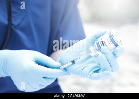 Medico femminile con stetoscopio su siringa con supporto per spalla e vaccino COVID-19. Concetto sanitario e medico. Foto Stock