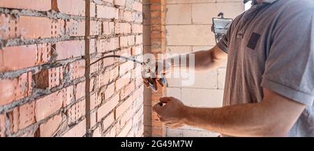 Un elettricista della costruzione taglia un cavo di tensione durante una riparazione. Foto Stock