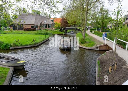 Uomo che guida una barca attraverso i canali del villaggio di Giethoorn noto anche come Venezia olandese Foto Stock