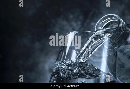 Versare l'acqua dalla bottiglia in vetro su sfondo nero Foto Stock