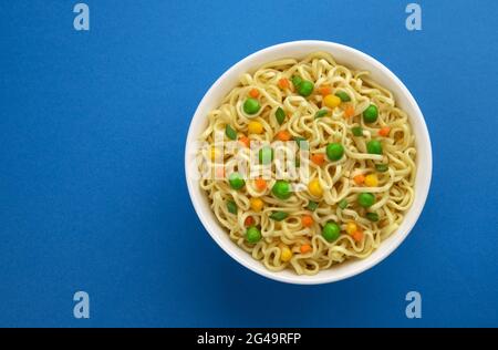 Ciotola di noodles istantaneo isolato su sfondo blu, vista dall'alto Foto Stock
