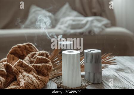 Accogliente composizione domestica con candele estintate su un tavolo di legno con un elemento a maglia. Foto Stock