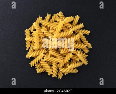 Pasta di fusilli grezzi isolata su sfondo nero, vista dall'alto Foto Stock