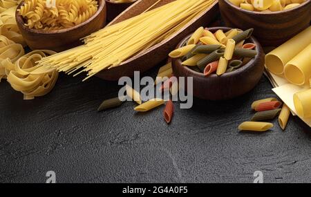 Diversi tipi di pasta su sfondo nero con spazio di copia per il testo Foto Stock