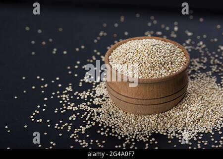 La quinoa semi in ciotola di legno su sfondo nero Foto Stock