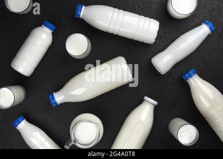 Confezionamento prodotti caseari, bottiglie e bicchieri con latte su sfondo nero, vista dall'alto Foto Stock