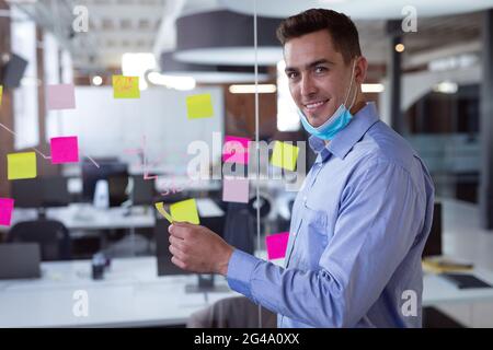 Ritratto di uomo d'affari caucasico in maschera abbassata brainstorming, sorridente alla macchina fotografica Foto Stock