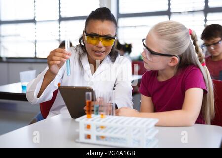 Insegnante femminile afroamericana che insegna chimica ad una ragazza durante la lezione di scienza in laboratorio Foto Stock