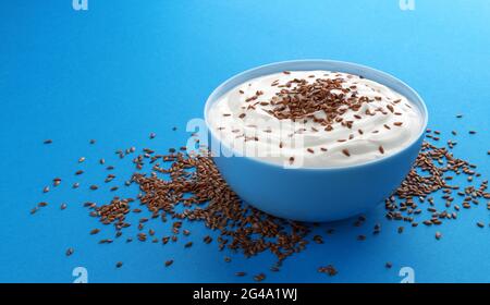 Yogurt con semi di lino isolato su sfondo blu Foto Stock