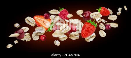 Fiocchi di avena volanti con bacche isolate su sfondo nero Foto Stock