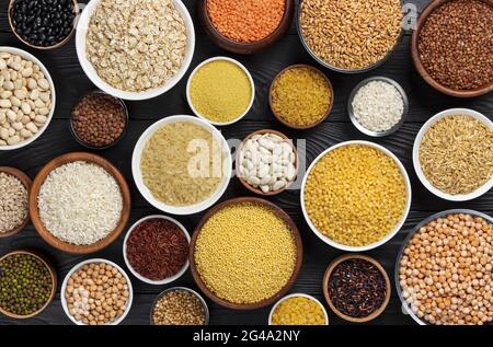 Cereali, granaglie, semi e semole e semolini di nero lo sfondo di legno Foto Stock