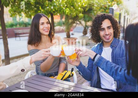 Gruppo multietnico di amici che brinda con le loro bevande mentre si beve insieme. Foto Stock