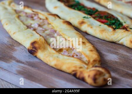 Un closeup di appetitosa varietà di pide flatbread ripieni di condimenti su una superficie di legno Foto Stock