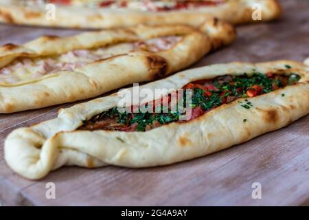 Un closeup di appetitosa varietà di pide flatbread ripieni di condimenti su una superficie di legno Foto Stock